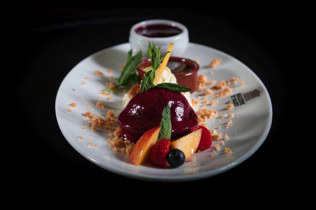 Elegant dessert featuring vibrant sorbet and fresh fruits on a white plate with garnish.
