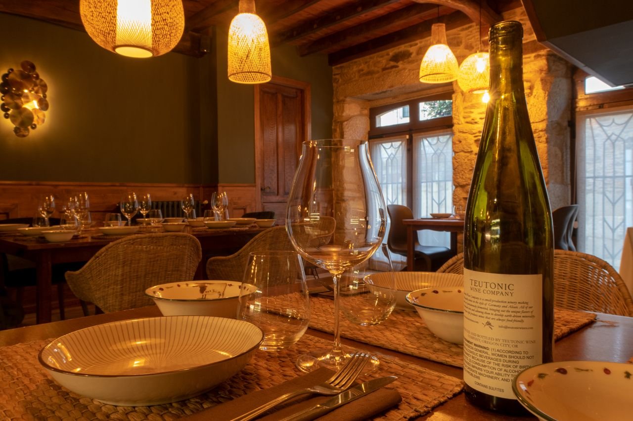 Warm, inviting dining scene with rustic table setting, wine, and elegant tableware in a cozy restaurant.