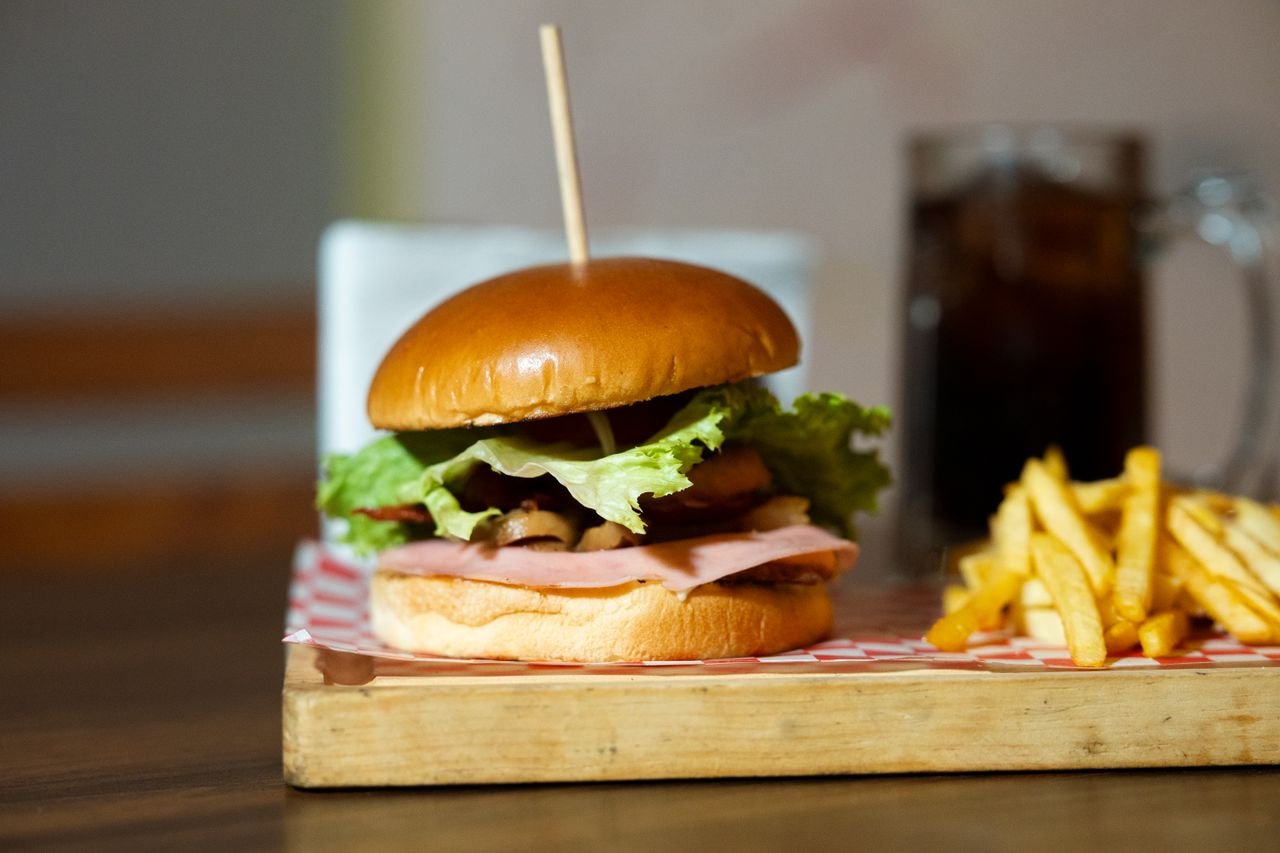 Mouth-watering burger with fries served on wooden board, perfect for fast food lovers.
